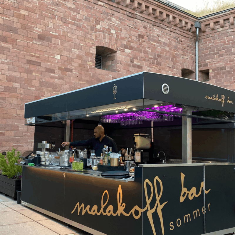Outdoor mobile bar and kitchen with people enjoying drinks