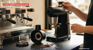 Barista brushing the exposed burr chamber of a commercial coffee grinder with the hopper removed on a cafe counter